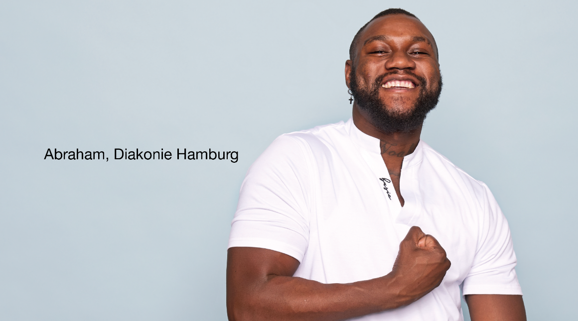 Person im weißen Hemd vor hellblauem Hintergrund hält eine Hand vor der Brust. Links Text 'Abraham, Diakonie Hamburg'.