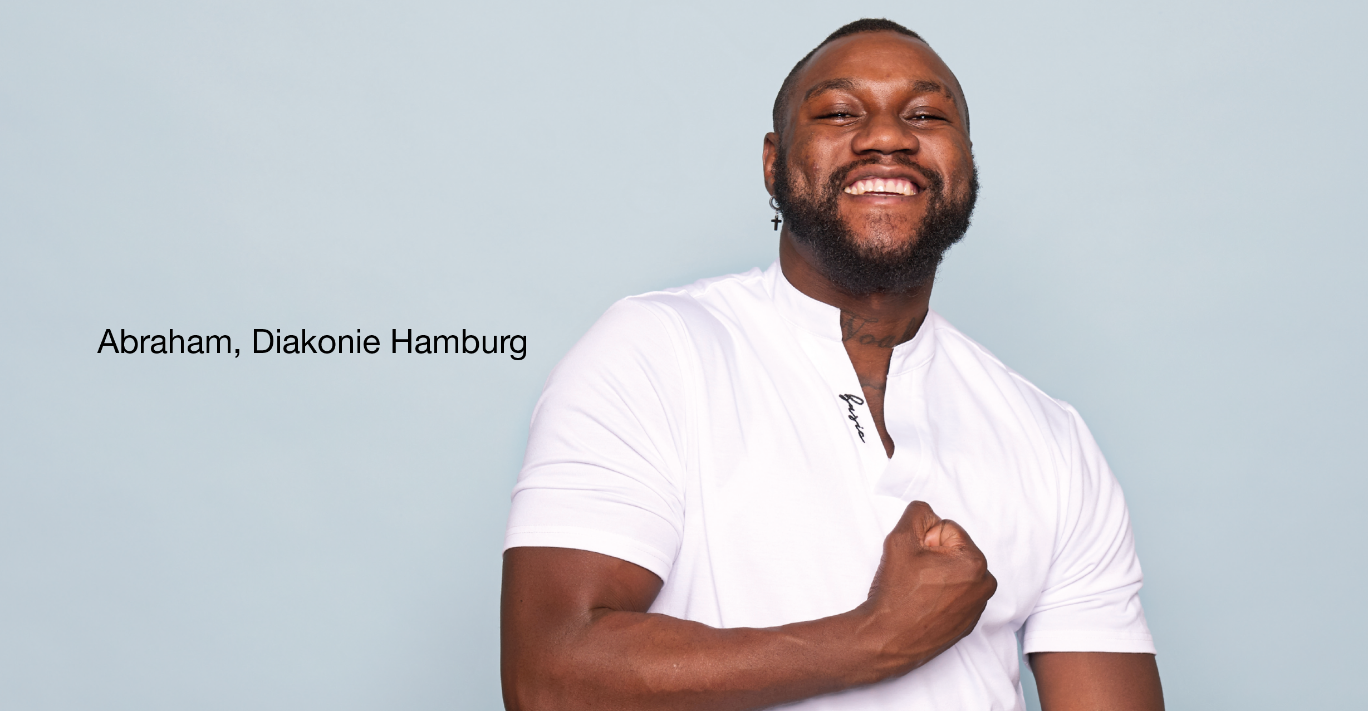 Person im weißen Hemd vor hellblauem Hintergrund hält eine Hand vor der Brust. Links Text 'Abraham, Diakonie Hamburg'.