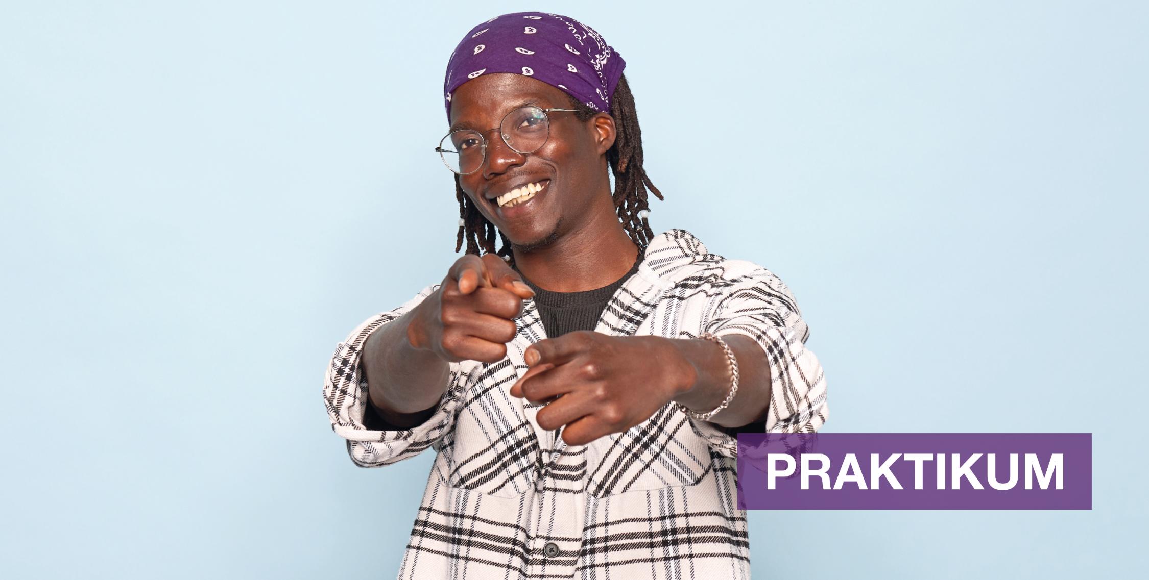 Person mit Brille und lila Kopftuch zeigt lächelnd mit beiden Händen zur Kamera. Kariertes Hemd, hellblauer Hintergrund, Text: „Praktikum bei der Diakonie Hamburg“.